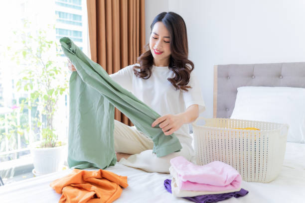 istock Young Asian woman folding clothes 1407834638
