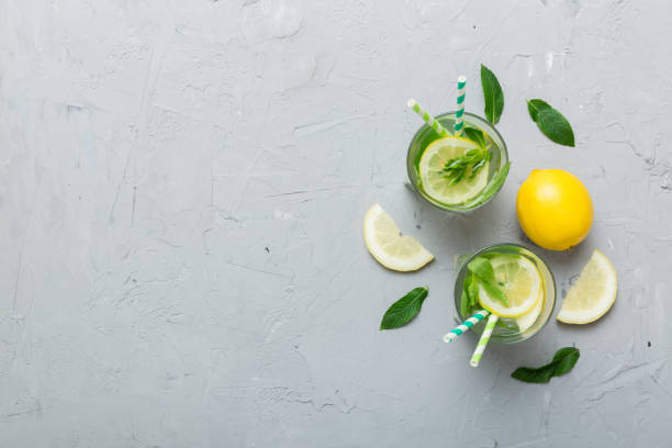caipirinha, mojito cocktail, vodka or soda drink with lime, mint and straw on table background. refreshing beverage with mint and lime in glass top view flat lay - drink on top of ice food imagens e fotografias de stock