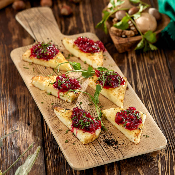 istock Hot appetizer for wine - grilled halloumi cheese with jam. Cheese appetizer baked halloumi on wooden background on rustic style. Adyghe cheese with berries dip on wooden table. 1407837363
