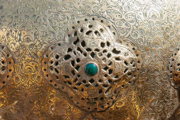 An Example Of Artistic Patterns On Metal. Fragment of a metal object with an insert of turquoise stone.Background.