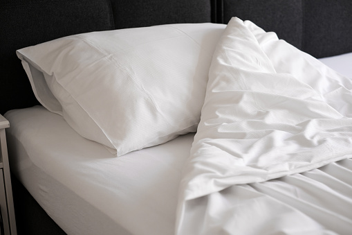 unmade bed with white linens close-up