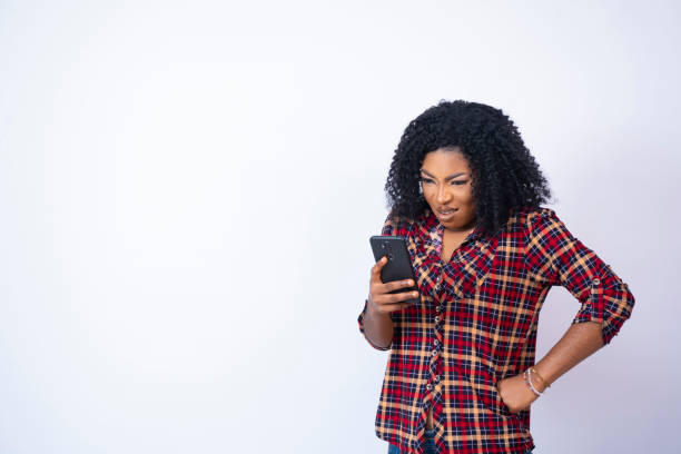 istock young back woman holding her phone looking displeased 1407844687