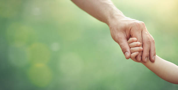 padri mano che tiene il suo bambino piccolo in una giornata di sole all'aperto, famiglia unita e concetto di infanzia felice, formato banner. - minute hand immagine foto e immagini stock