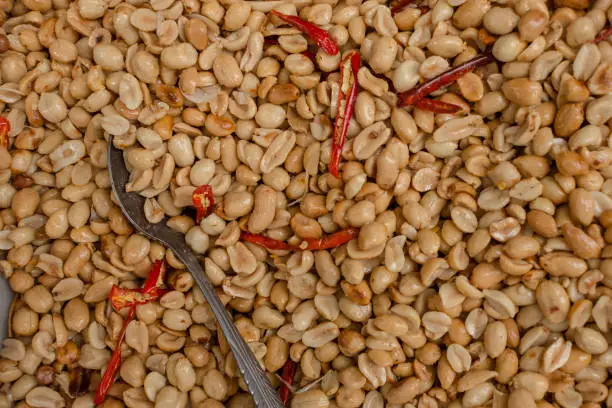 Photo of Closeup of skinless and salted roasted peanuts with red chili labuyo peppers for sale at a stall.