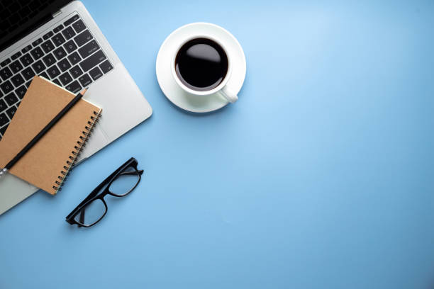 istock Flat lay, top view office table desk. Workspace with, laptop,office supplies, pencil, green leaf, and coffee cup on blue background. 1407846952