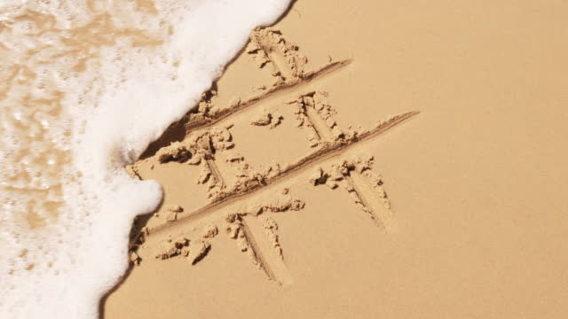 Hashtag in the sand on a beach washed away by the sea.
