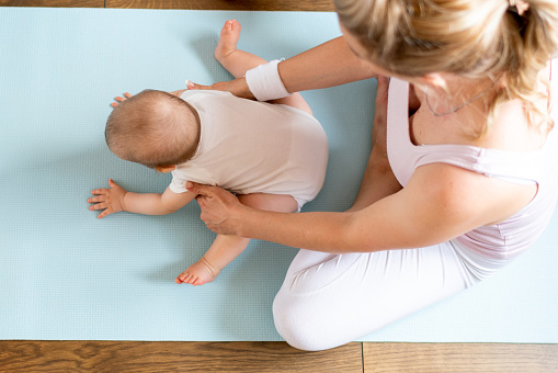 Mother doing postnatal exercises with her baby at home