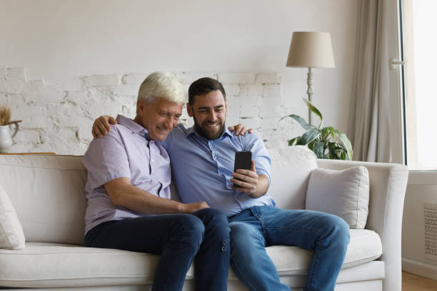 istock Grownup son his older father having fun using modern smartphone 1407852349