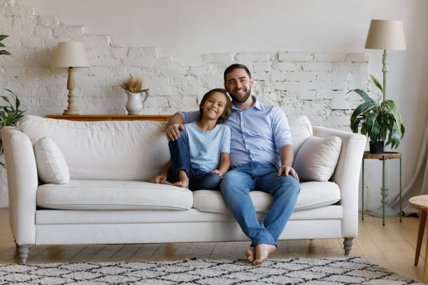 istock Little boy young father sit on sofa look at camera 1407852369