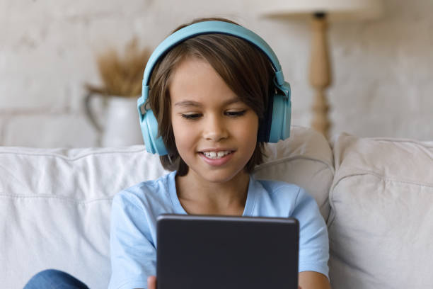 istock Attractive little boy wear headphones have fun using digital tablet 1407852774