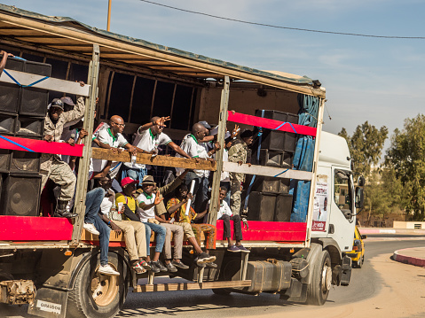 Dakar, Senegal - February 3, 2019: Africans sit on a truck, shout and show a sign of freedom during a street manifestation. Africa.