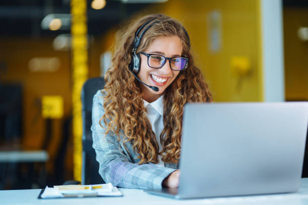 Female customer service representative in a headset is consulting clients online. stock photo