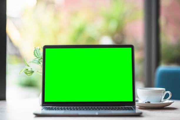 istock Mockup of laptop computer with empty screen with coffee cup and smartphone on table of the coffee shop background,Green screen 1407857805