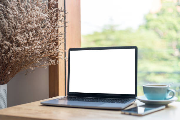 istock Mockup of laptop computer with empty screen with coffee cup and smartphone on table of the coffee shop background,White screen 1407859407