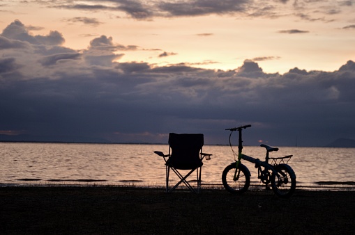 Empty chairs beside bicycles on the beach  twilight  with strong black clouds in rainy season concept relaxation weather forecast travel vacation copy space