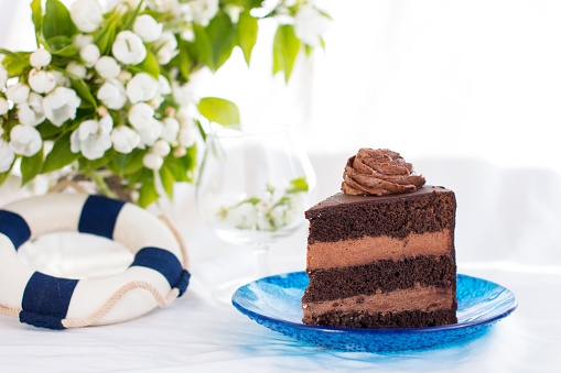 a piece of chocolate cake on a blue plate. Beautifully decorated confection
