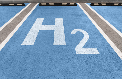 H2 symbol on a blue asphalt. Hydrogen powered cars refueling parking