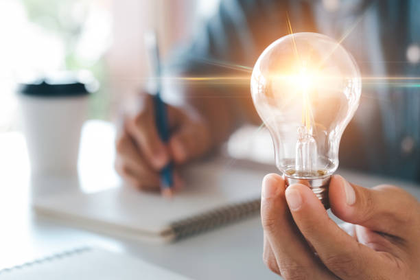 アイデアとインスピレーションのアイデアによるイノベーション。照明を照らす電球を持つ人間の手、創造性のアイデアと持続可能なビジネス開発のインスピレーションの概念。 - アイデア ストックフォトと画像