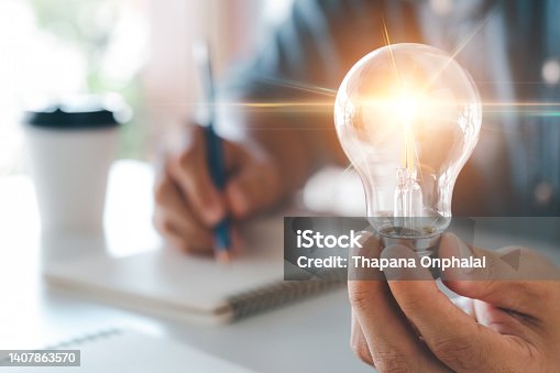 istock Innovation through ideas and inspiration ideas. Human hand holding light bulb to illuminate, idea of creativity and inspiration concept of sustainable business development. 1407863570