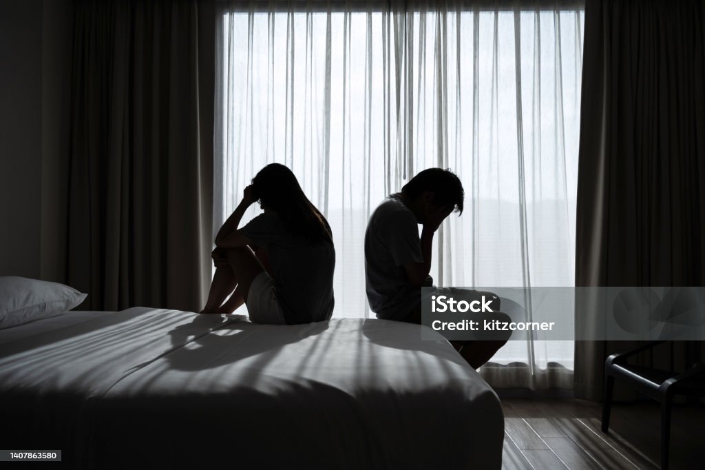 Depressed couple having a problem sitting head in hands in the dark bedroom, Negative emotion and mental health concept Couple - Relationship Stock Photo