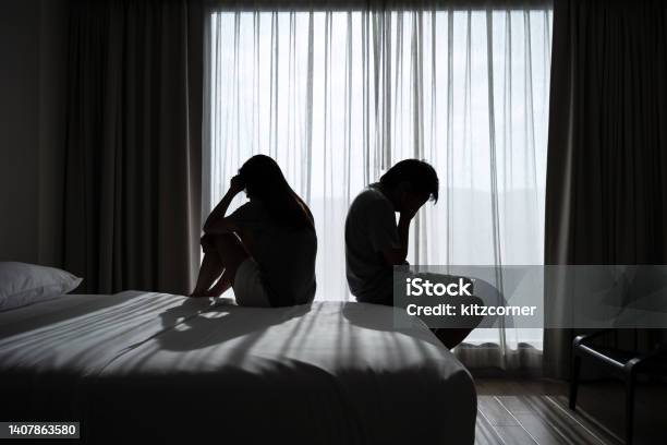 Depressed Couple Having A Problem Sitting Head In Hands In The Dark Bedroom Negative Emotion And Mental Health Concept Stock Photo - Download Image Now
