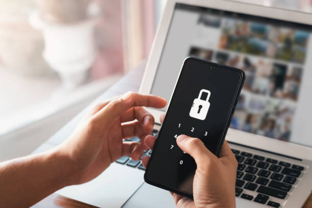 istock Hacking a Phishing mobile phone with a password to access a smartphone, security threats online, and fraud. A young man with a cell phone and laptop is secure in his bank account. 1407863830