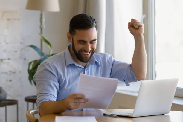 istock Man holding papers read information looks overjoyed, celebrate success 1407865340