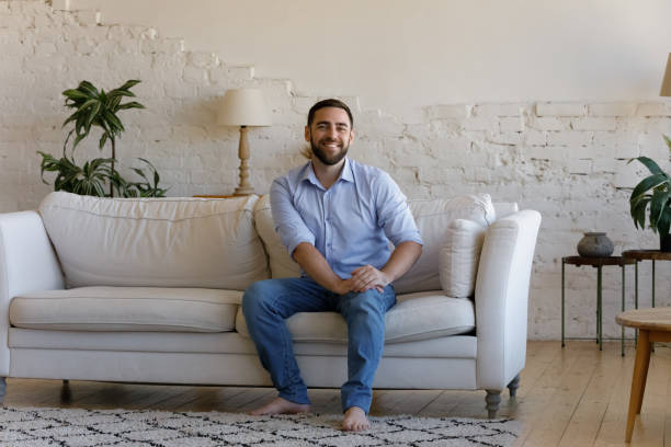 istock Satisfied handsome man sit on sofa smile look at camera 1407865365