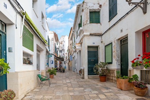 A picturesque street of shops and cafes in the historic old port town of the city of Mahon, Spain, on the Balearic island of Menorca Spain in the Mediterranean Sea.