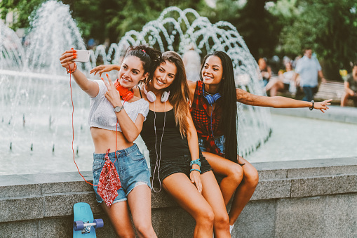 Girls enjoying new city and taking photos with smartphone