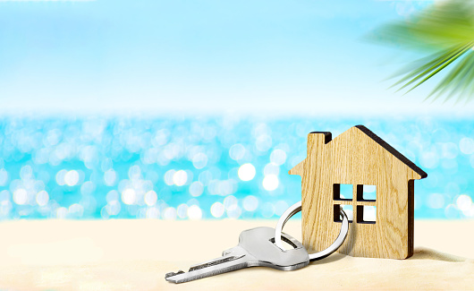 Concepto de casa junto al mar. Figura de casa y llave en playa de arena photo