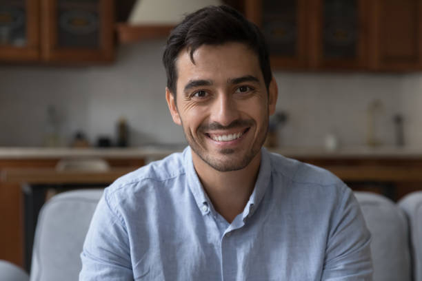 istock Hispanic man sit on sofa at home look at camera 1407878236
