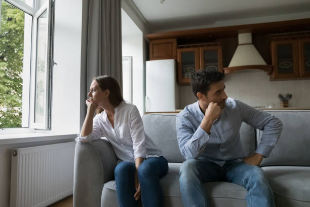 istock Sad young couple sit apart on sofa after quarrel 1407878249