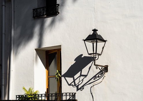 Classic style lamppost, casts shadows on a whitewashed wall