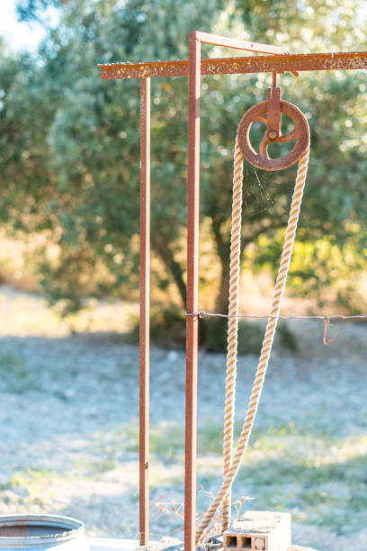 istock Rusty metal pulley with rope outside a well 1407879213