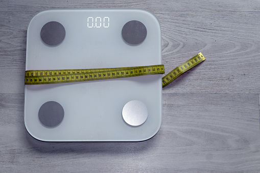 Symbolic image for diet and weight control: scale with tape measure