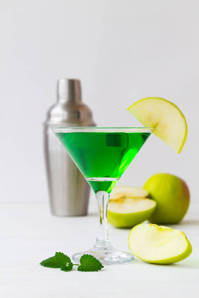 istock Apple cocktail mixed drink with vodka and apple slice. Apple martini cocktail on the white table. Green Alcoholic drinks in martini glasses with apple slice and shaker. copy space. vertical 1407889427