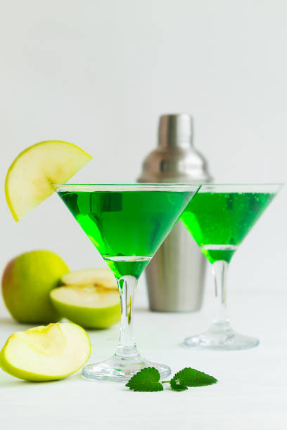 istock Apple cocktail mixed drink with vodka and apple slice. Apple martini cocktail on the white table. Green Alcoholic drinks in martini glasses with apple slice and shaker. copy space. vertical 1407889440