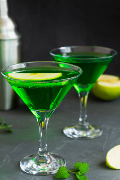 istock martini with mint.Apple cocktail mixed drink with vodka and apple slice. Apple martini cocktail on the black background. Green Alcoholic drinks in martini glasses with apple slice. 1407889463
