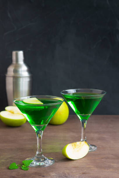 istock Apple cocktail mixed drink with vodka and apple slice. Apple martini cocktail on the black background. Green Alcoholic drinks in martini glasses with apple slice. copy space. 1407889471
