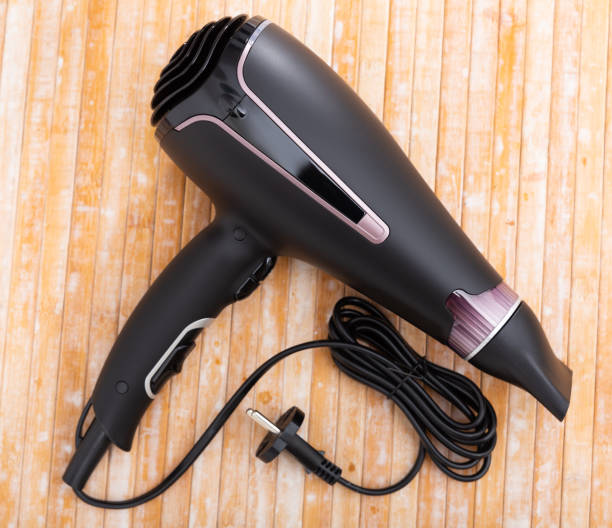 istock Black blow dryer on wooden surface 1407889996