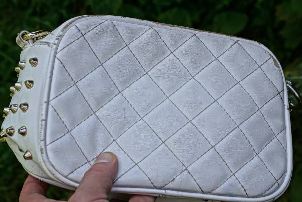 istock hand holding one old shabby white leather bag 1407895550