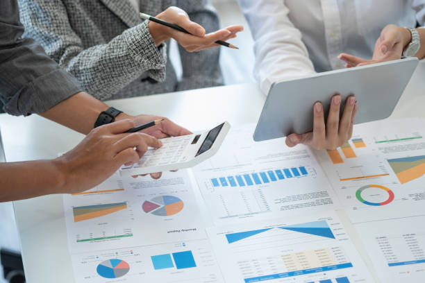 istock Team of business use calculators and graph analysis computer laptop tablets to plan marketing strategies and make profitable investments for the company. 1407895935