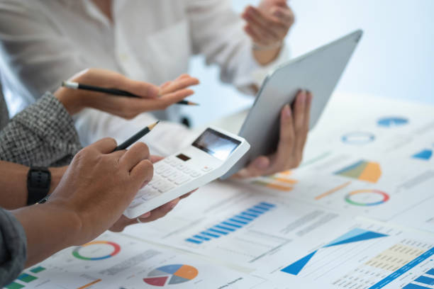 istock Team of business use calculators and graph analysis computer laptop tablets to plan marketing strategies and make profitable investments for the company. 1407895956