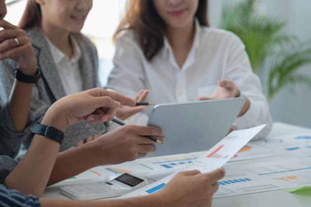 istock Team of business use calculators and graph analysis computer laptop tablets to plan marketing strategies and make profitable investments for the company. 1407896102