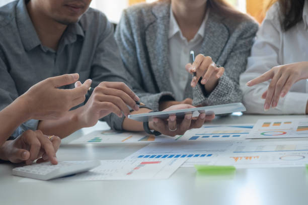 istock Team of business use calculators and graph analysis computer laptop tablets to plan marketing strategies and make profitable investments for the company. 1407896180