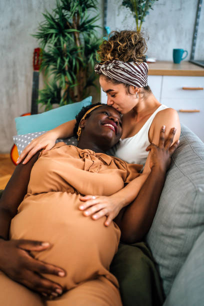istock Pregnant lesbian couple relaxing on sofa 1407896183