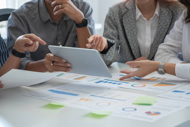 istock Team of business use calculators and graph analysis computer laptop tablets to plan marketing strategies and make profitable investments for the company. 1407896300