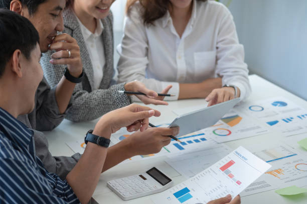 istock Team of business use calculators and graph analysis computer laptop tablets to plan marketing strategies and make profitable investments for the company. 1407896312