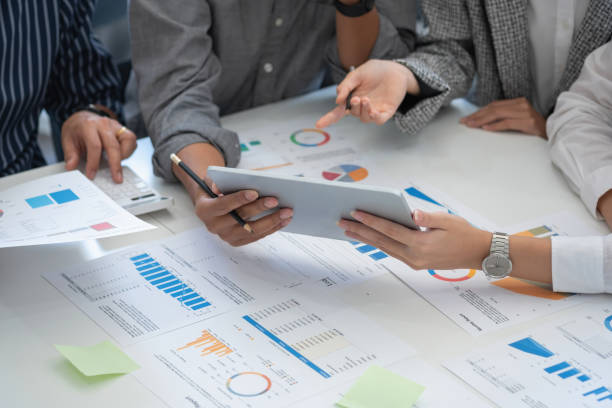 istock Team of business use calculators and graph analysis computer laptop tablets to plan marketing strategies and make profitable investments for the company. 1407896345